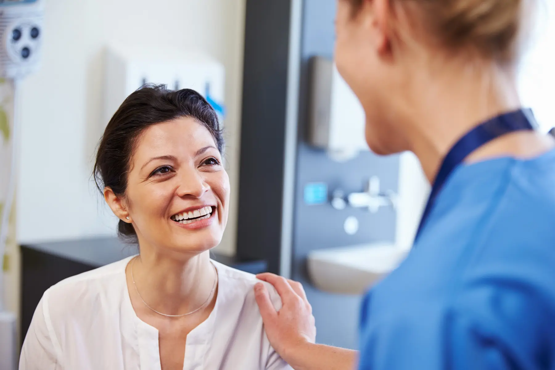 Smiling patient engaged in a positive conversation with a healthcare professional in a medical office setting, highlighting the importance of patient care and communication.